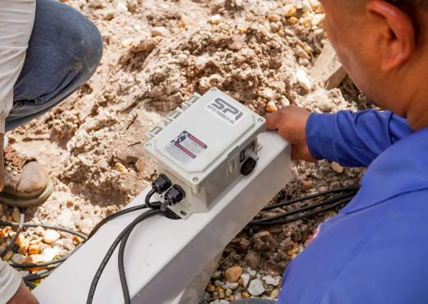 Technician servicing a septic pump control panel and alarm