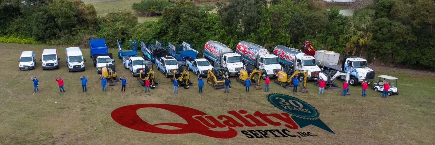 The Quality Septic team in front of their branded service fleet